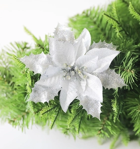 Close-up of glittery silver Christmas flower decoration on green artificial pine branches