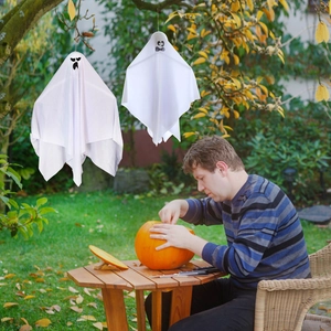 White hanging ghost decorations for Halloween garden party with pumpkin carving scene