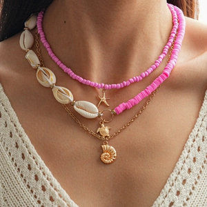 Detail of layered beach necklace featuring pink beads, gold starfish and sea turtle charms