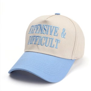 Close-up of blue embroidery text Expensive & Difficult on a five-panel baseball cap