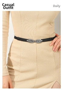 Detail of silver leaf-shaped metal buckle on a black slim waist belt for women
