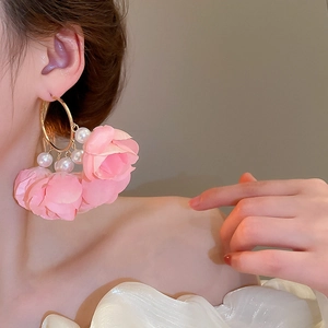 Detail of floral tassel earrings with pink fabric petals and white pearls on gold hoops