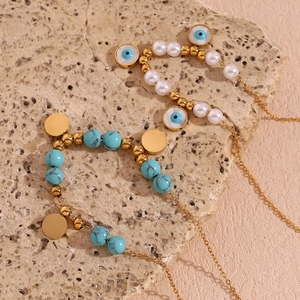 Detail of 18K gold plated necklaces featuring blue turquoise, pearls, and evil eye charms