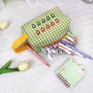 Close-up of green checkered pencil case with heart embroidery and yellow handle grip