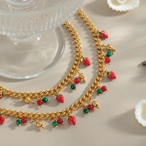 Vista macro di ciondoli a fragola e perle placcati in oro 18K su eleganti cavigliere