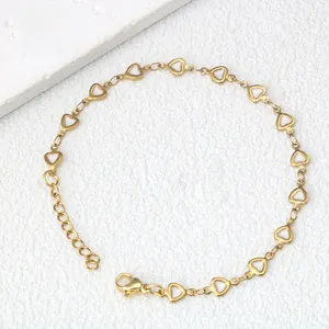 Dettaglio di un bracciale dorato a cuore con smalto bianco e chiusura regolabile