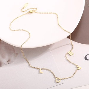 Détail du pendentif lettre LOVE doré sur un collier en acier inoxydable poli pour femme