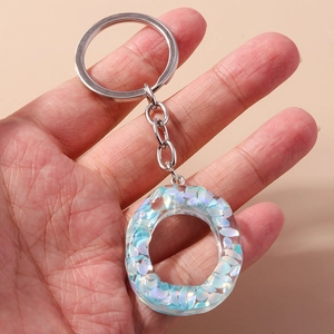 Close-up of light blue resin keychain with sparkling sequins and silver metal ring