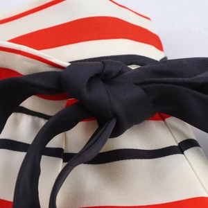 Macro shot of striped fabric with a central black silky knot detail and fine knit texture