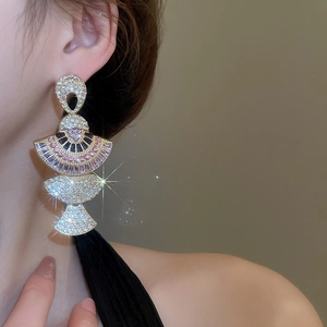 Detailed shot of a gold fan-shaped earring set with colorful crystals on a model
