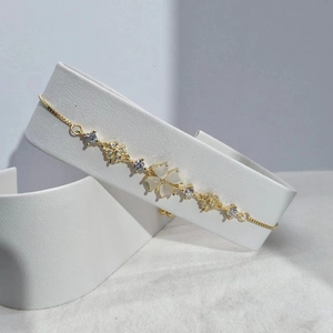 Detail of adjustable gold clover bracelet with white cat-eye stone and cubic zirconia