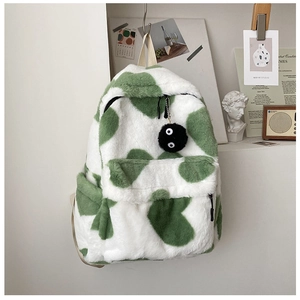 Detail of green and white cow print plush backpack with a cute soot sprite keychain
