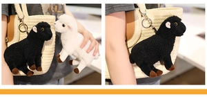 Détail de porte-clés mouton en peluche noir et blanc avec crochets sur un sac tissé
