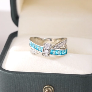 Macro shot of silver crisscross ring with blue cubic zirconia in a green jewelry box