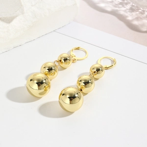 Detail of three-tier gold-plated graduated spheres on dangling chain earrings