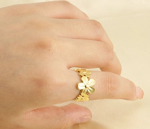 Detailed view of floral stainless steel ring with matte gold finish worn on finger