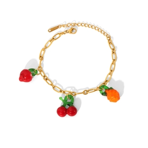 Close-up of golden stainless steel bracelet with red cherry and fruit charms