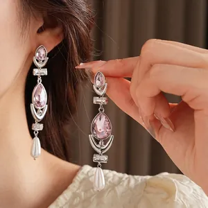 Elegant silver earrings with pink teardrop crystals and pearl drops on a female model