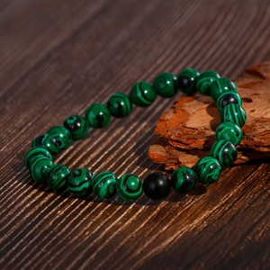 Unisex malachite beaded bracelet with matte black onyx accent on rustic wood