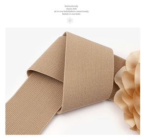 Detailed shot of beige elastic knitted waist belt featuring a 3D floral accent decoration