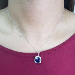Detail view of silver necklace with square blue faceted stone and pave diamonds on model