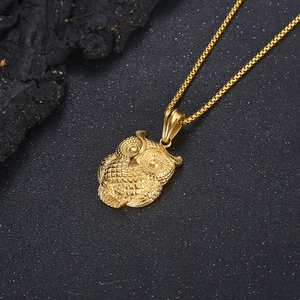 Detailed view of a golden owl pendant with a box chain on a textured dark background