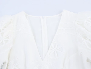 Détail de robe blanche à col en V avec broderie dentelle florale et zip invisible