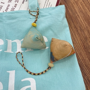 Detail of vintage zongzi fabric charms with colorful tassels on a canvas bag