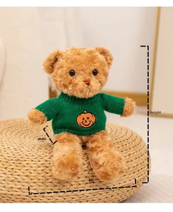 Ours en peluche avec un pull d'Halloween à citrouille verte sur un tapis en herbe