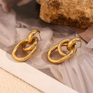 Détail des boucles d'oreilles géométriques entrelacées plaquées or 18 carats sur tissu