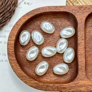 Close-up of white oval imitation pearl beads arranged in a natural wooden display tray