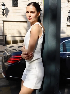 Women's chic white sleeveless blazer vest and high-waist shorts set in minimalist urban style