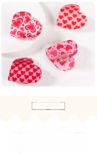 Close-up of four pink heart hair clips featuring red patterns on a clean white background