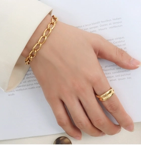 Detail of 18k gold plated chunky chain bracelet and wavy ring on a model's wrist