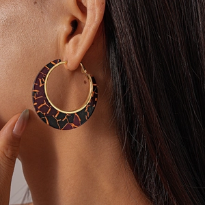 Detail of vintage geometric hoop earrings with purple resin texture and golden metal accents