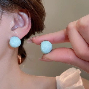 Detail view of light blue resin stud earrings with a marble texture on the surface
