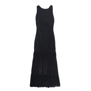 Detail view of the black sleeveless dress with layered mesh patchwork and pleated hemline