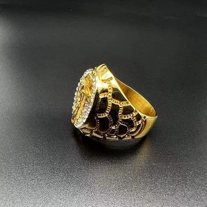 Close-up of gold-plated hip hop ring featuring religious Virgin Mary relief and clear crystals