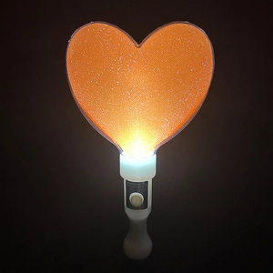 Macro shot of an orange heart glow stick with glitter particles and white handle