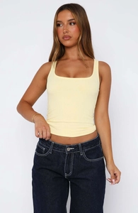 Detail showing the light yellow ribbed knit camisole with a square neck and slim fit