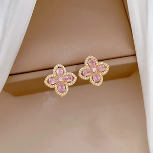 Detail of pink pear-shaped clover earrings with white crystal borders in gold setting