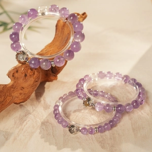 Detailed close-up of purple amethyst bracelets with hollow cat charm on natural wood