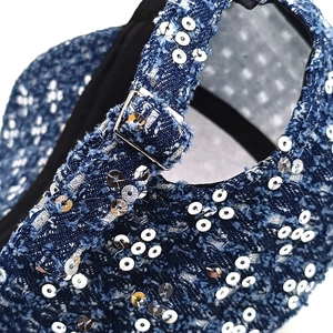 Close-up of distressed denim baseball cap with silver sequins and metal buckle