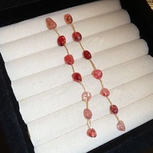Detail view of long tassel earrings with strawberry quartz beads in a jewelry box