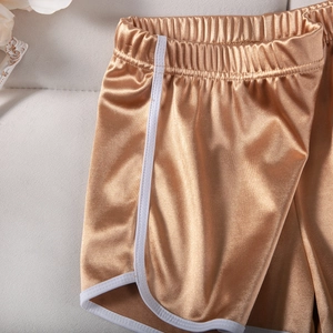 Detail of metallic golden sports shorts on beige fabric with floral decoration