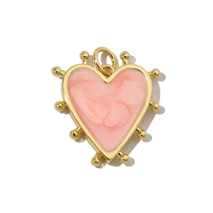 Macro view of pink pearlescent heart pendant with gold plating and beaded edge trim
