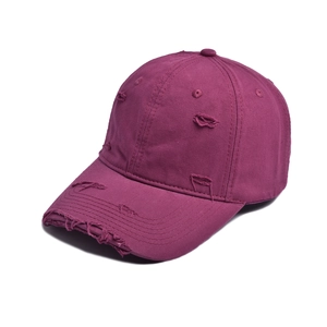 Close-up of distressed wine red baseball cap with vintage frayed edges and ripped details