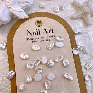 Detailed view of irregular baroque pearl nail art charms on a decorative display card