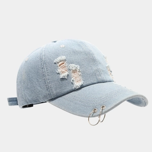 Distressed light blue denim baseball cap with silver metal rings and frayed hole details