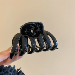 Detailed view of a sleek black bow hair claw clip with a glossy finish and smooth edges